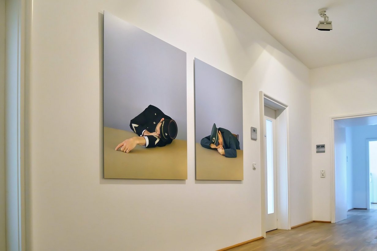 Zwei Fotografien im weiß gestrichenen Vorraum des Büros des Regionalverbandsdirektors. Sie zeigen einen deutschen und einen französischen Zöllner, die über eine Tischplatte gebeugt schlafen.